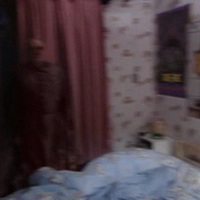 A screenshot from Ghostwatch (1992), depicting an ominous figure standing in a child's bedroom.